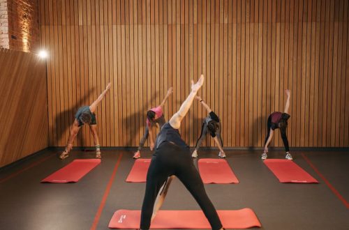 Yoga class with diverse adults stretching on mats in a cozy wooden studio.